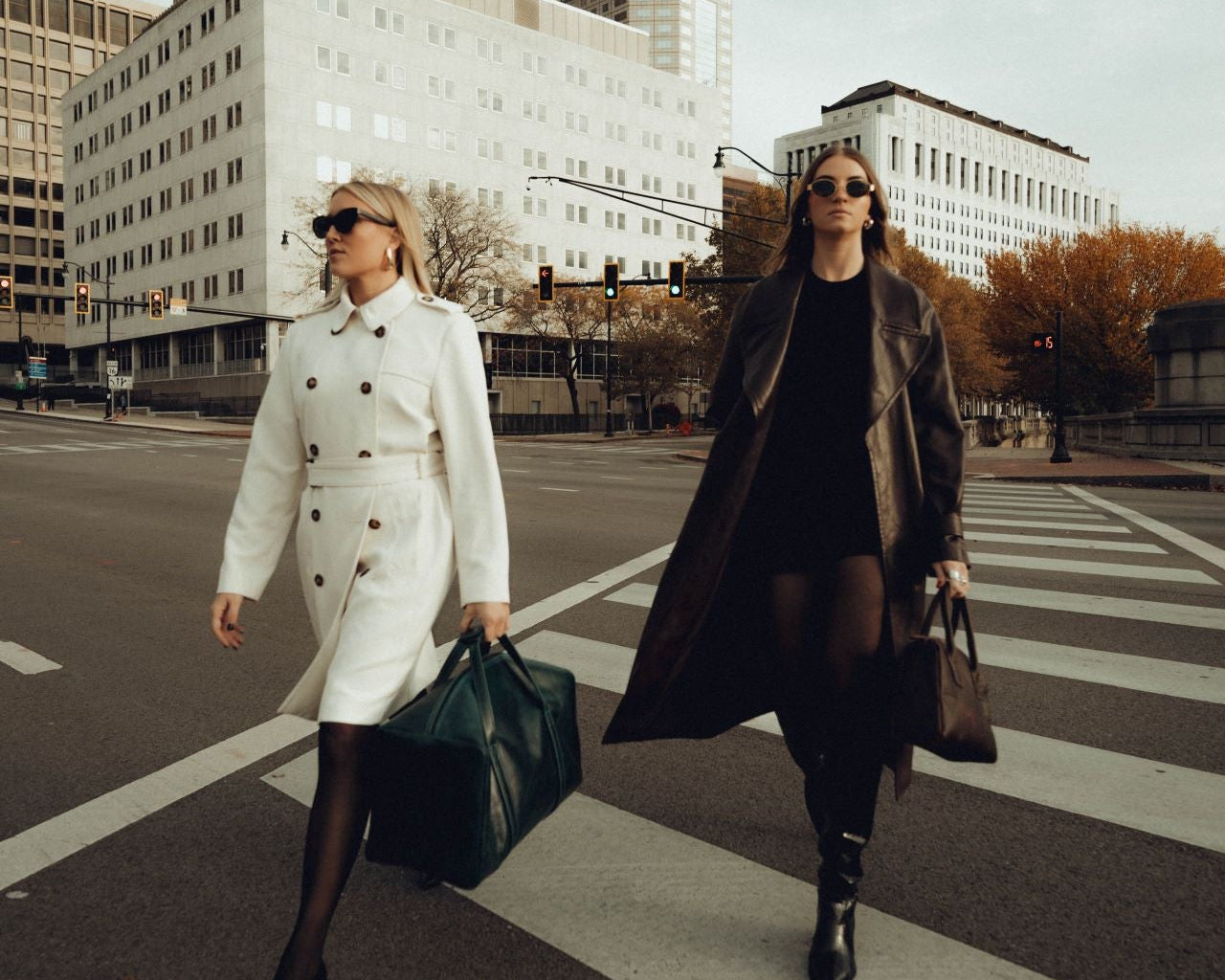 Two women walking on a city street with modern buildings in the background